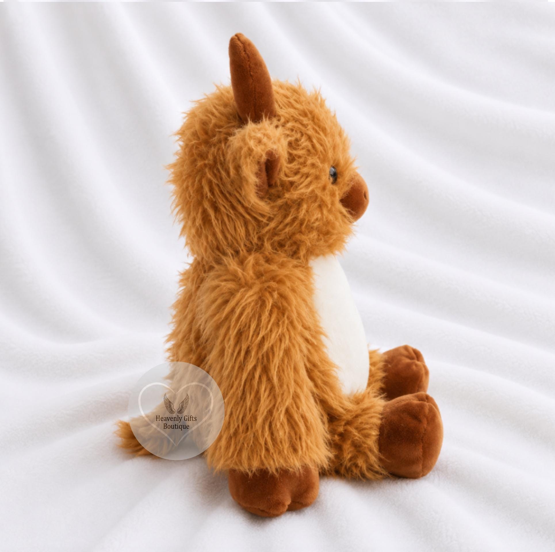 A fluffy brown plush alpaca toy with a white chest, sitting on a white draped fabric background.