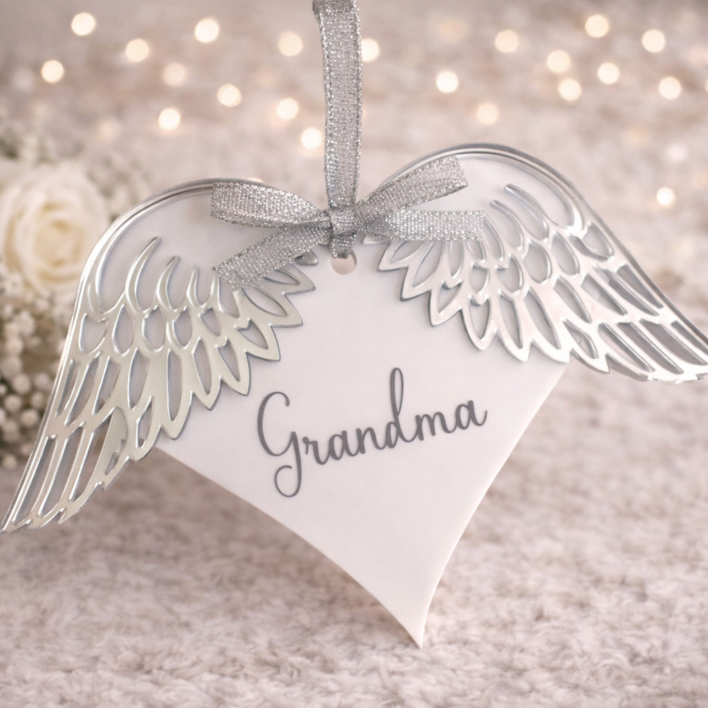 Personalised angel wings memorial decoration displayed on a white stand