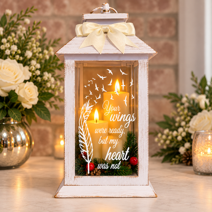 Christmas memorial lantern with festive wreath and bow displayed alongside flowers and candlelight