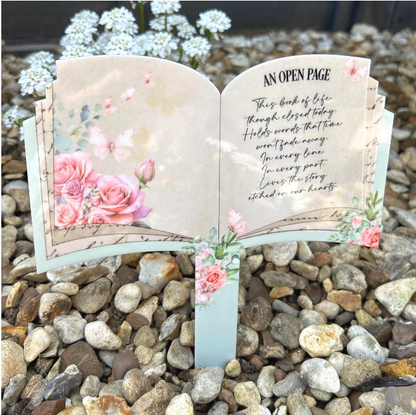 Pink rose and butterfly open book grave marker featuring the An Open Page memorial poem in an outdoor graveside setting