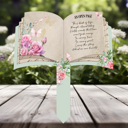 Open book memorial grave marker with pink roses and butterflies featuring the An Open Page remembrance poem