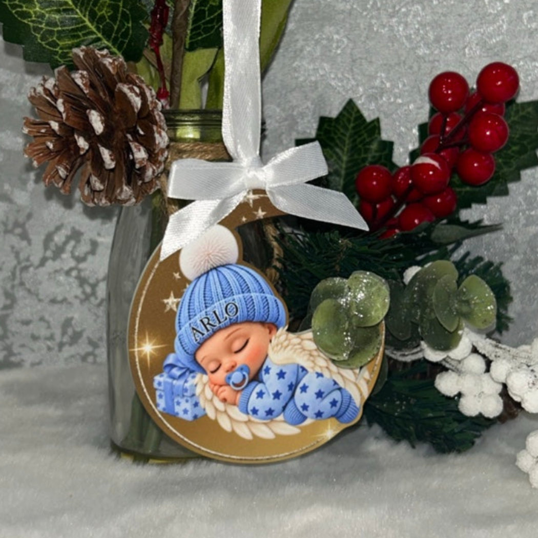 Real photograph of blue Sleeping Angel Baby memorial bauble with optional name Arlo, white ribbon and bow, displayed beside festive berries and white flowers.